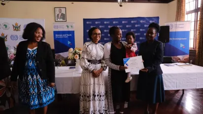 Line up of officials at the certificate handover ceremony with a trainer receiving carrying her baby