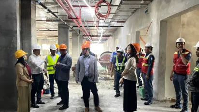 Several individuals in safety helmets are gathered in a construction site. 