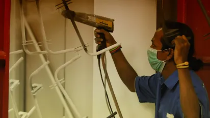 a male worker spraying the racks holders into white color