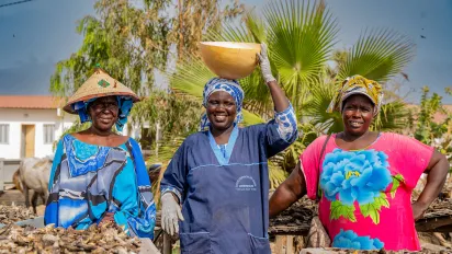 Portrait of Yaye Coumba Seck, smiling at the centre, alongside two fellow members of the women’s fish-processing cooperative in Mbao. (Mbao, Dakar, Senegal, 2025)