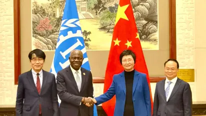 Gilbert F. Houngbo, Director-General of the ILO, with Wang Xiaoping, Minister of Human Resources and Social Security of China shaking hands in front of their flags