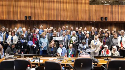 Many participants in a meeting standing for a family picture