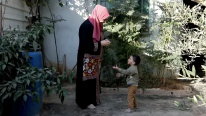 Tailor Hanan Khaled Al-Khawalda plays with her two-year-old son, Ahmad, in the patio of their home in Jordan’s Za’atari camp for Syrian refugees on October 28, 2025. 