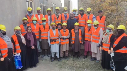 Group photo of infrastructure workers wearing orange vests and yellow helmets