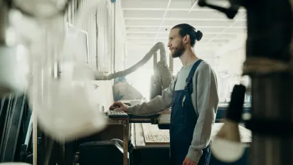 A factory worker stands in front of a computer