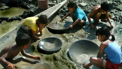 children searching for gold and using heavy metal pans