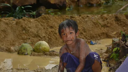 a young boy filled with mud searching for gold