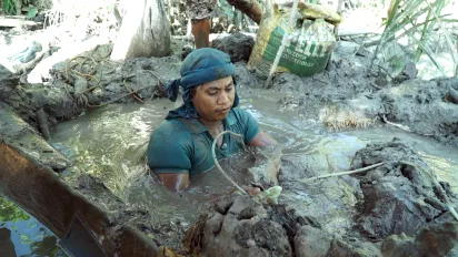 a male worker in small scale gold mining on muddy water