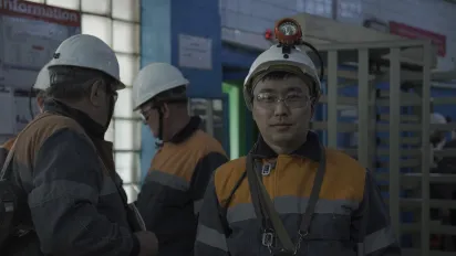 Men wearing helmets and protective equipment inside an industrial facility