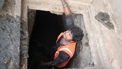 A sanitation worker standing inside a drainage manhole.