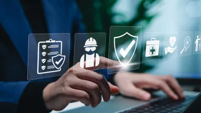 A person using a laptop with digital icons representing work safety, compliance, regulations, and professional standards, symbolizing secure workplace practices.