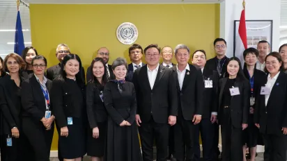 A group of officials and staff members pose for a formal photo in an office setting.