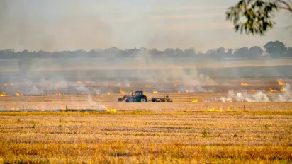 Farming truck in a field with fire
