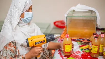 Reshma Akhter preparing vinegar bottle for selling