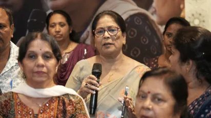 A woman speaks into a microphone while other participants listen around her.