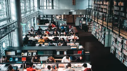 Persons sitting in the reading room of a library