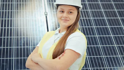 Young woman in front of solar panels wearing a hard hat 