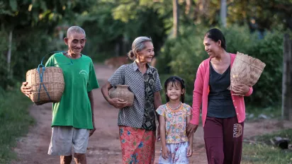 Three generations of a family walk together along a rural road.