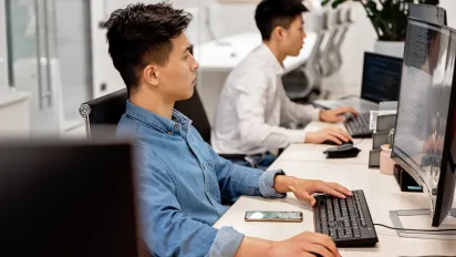 Young professionals working on computers in a modern office environment, focused on their tasks.