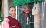 Eyad Al Merjawi, a 41-year-old refugee from Syria, standing in front of the butcher shop where he works