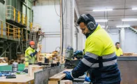 Carpenter wearing safety equipment, assembling wooden pallets in a recycling plant 