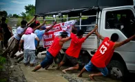 A group of volunteers helping a truck get out of the mud