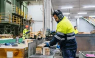 Three men working with wood in a factory, 2 operating machinery and wearing ear defenders and hard hats 