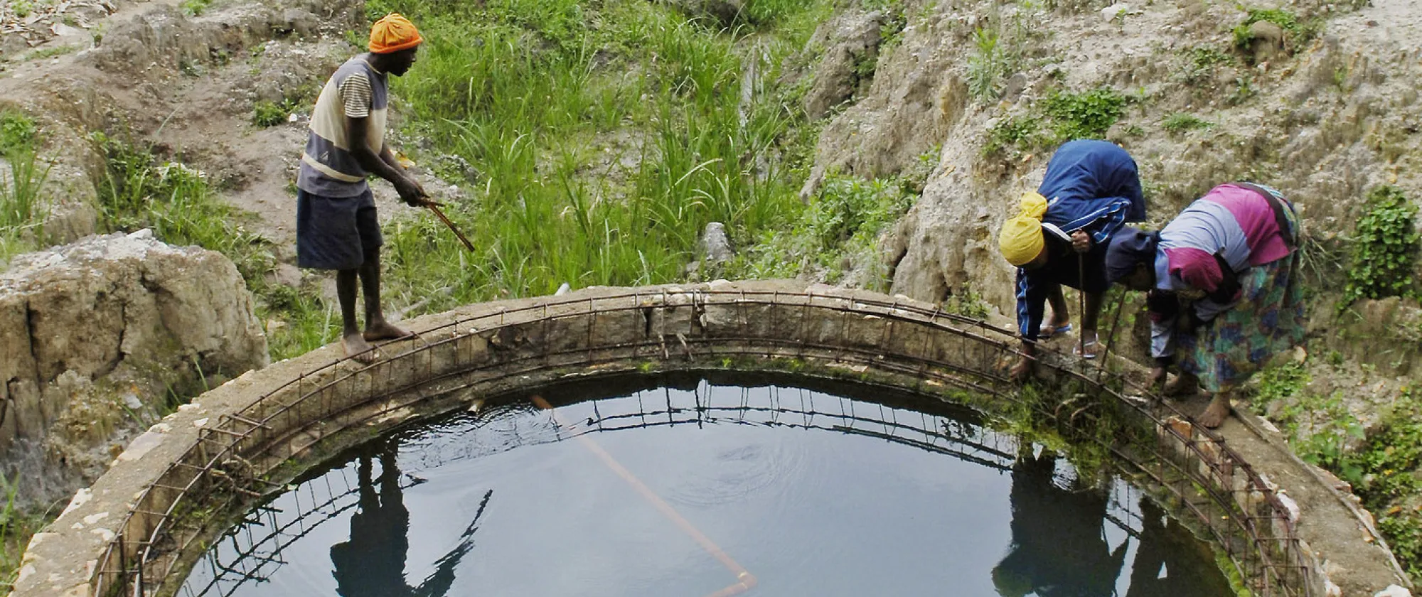 Men standing around a water reservoir used for crop irrigation in Rwanda