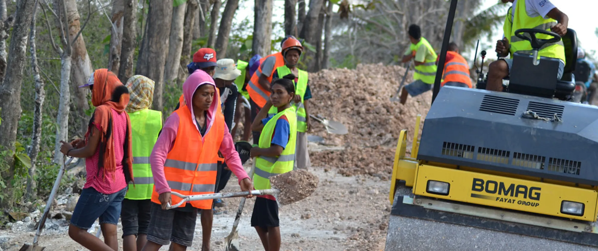 Women and men construction workers wearing protective equipment on the side of the road they are building