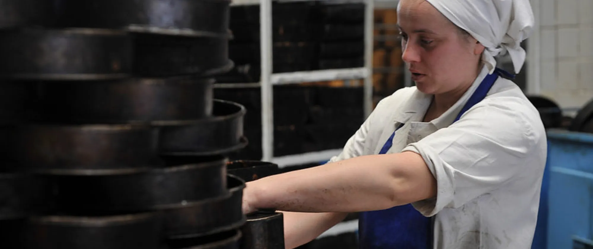 Young woman rearranging cake molds in industrial kitchen