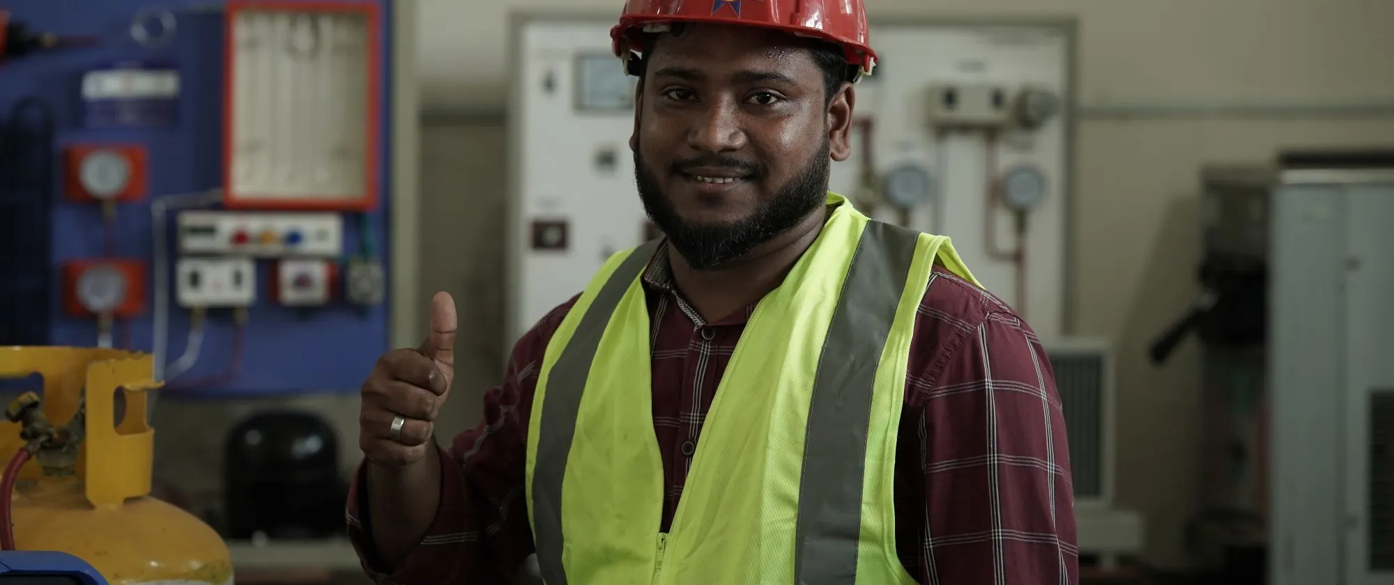 A Bangladeshi man in protective gear shows thumbs up sign