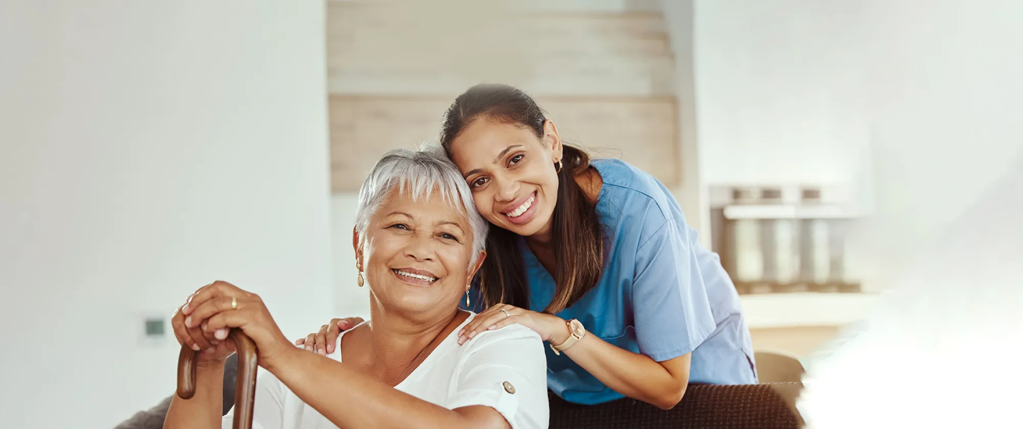 A smiling social worker helping senior woman holding a walking stick in her hand