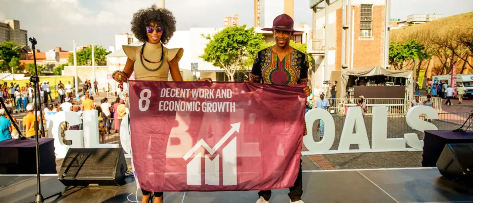 A man and a woman holding a SDG goal 8 flag on decent work and economic growth