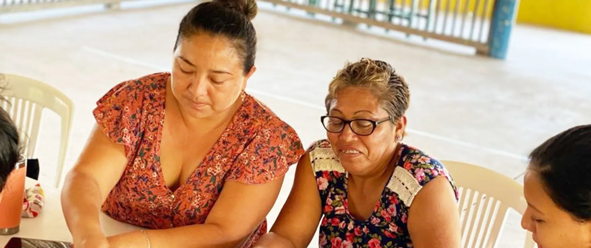 Four women sitting at a table sorting beads