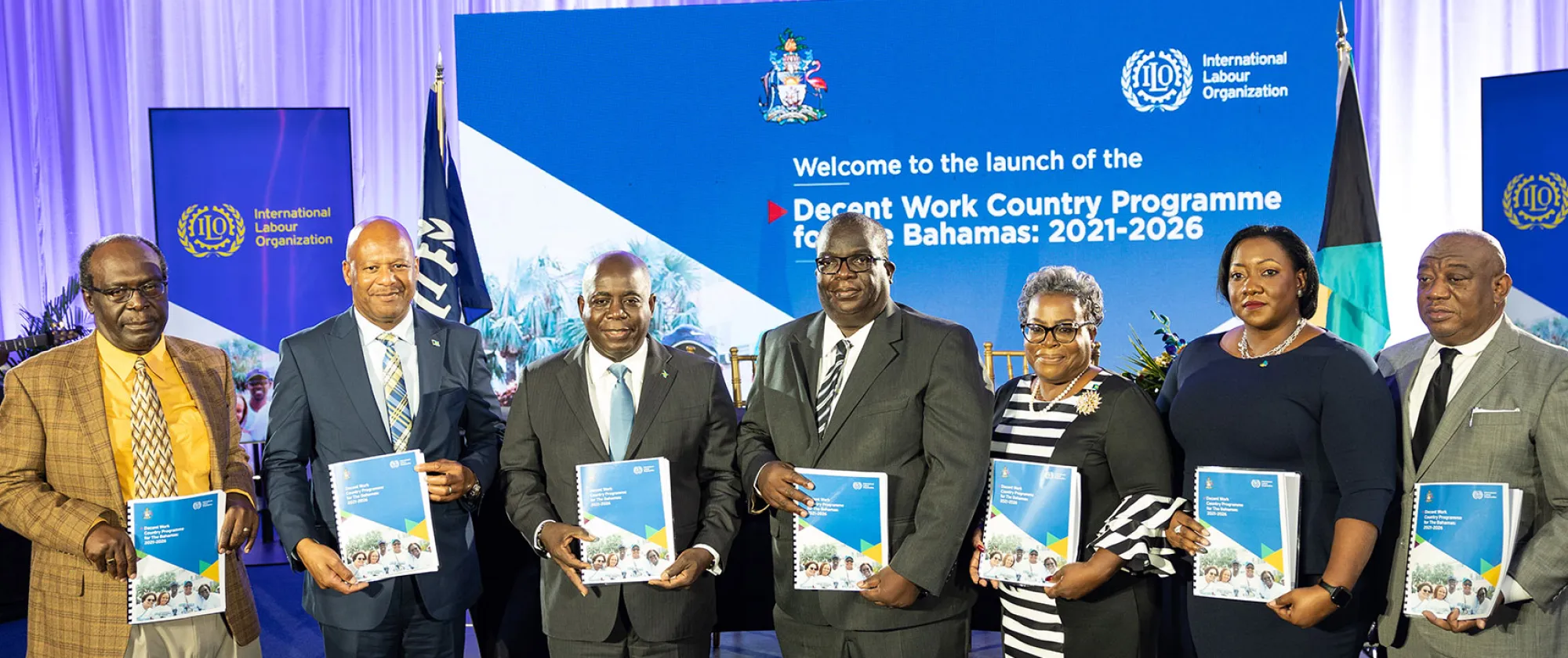 Seven people standing with documents in their hands