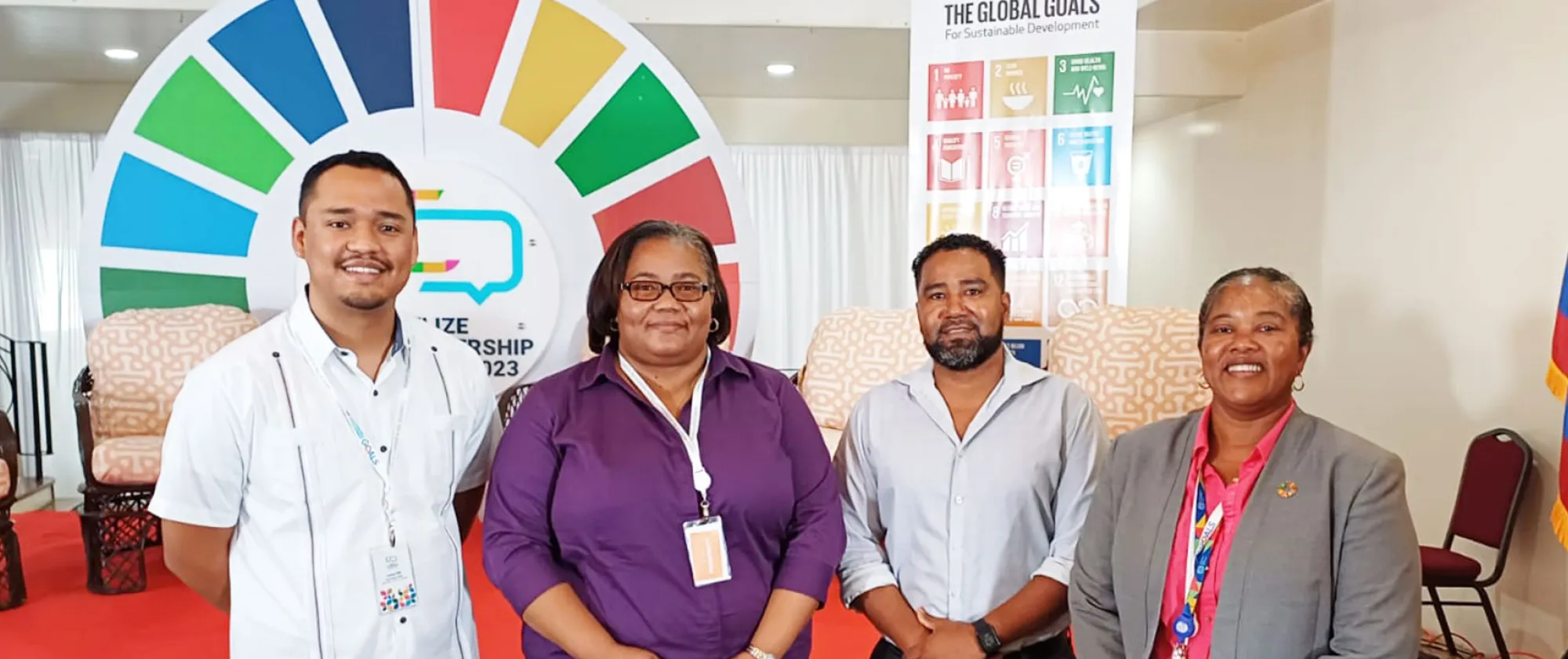 Four people standing in front of SDG signage