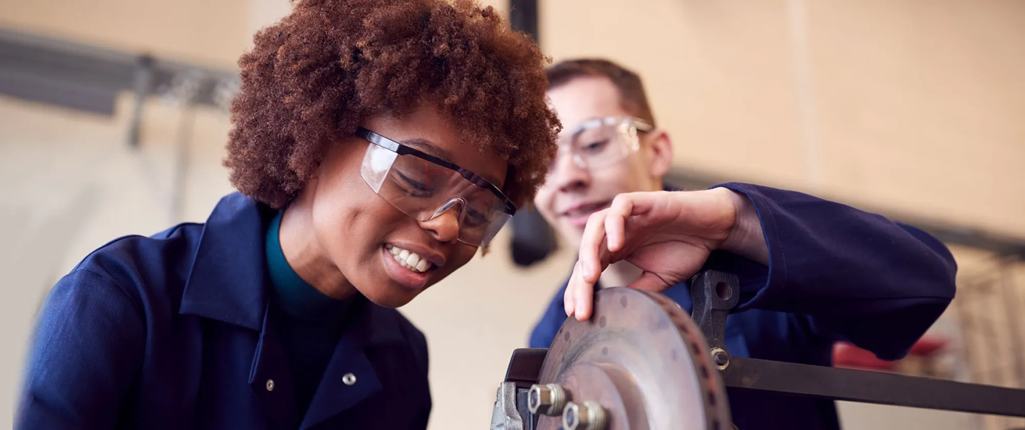 Male And Female Students Working On Car Brakes On Auto Mechanic Apprenticeship Course At College