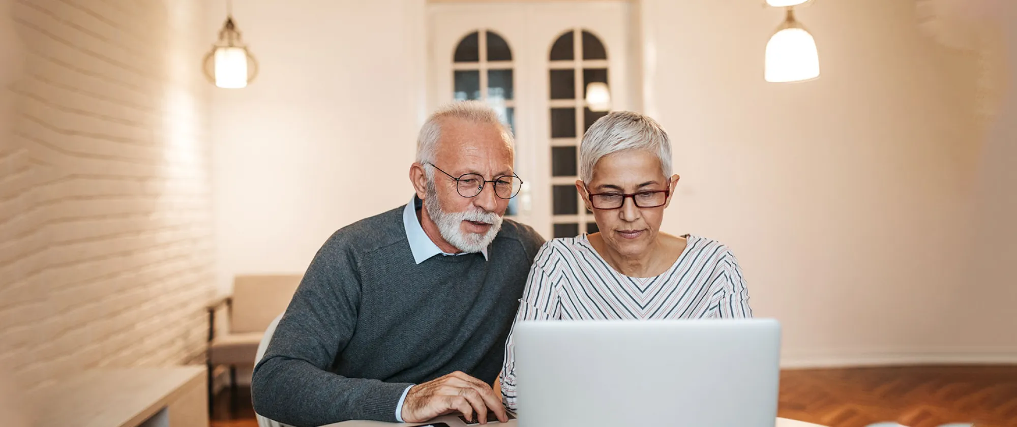 A retired couple looking at a laptop screen