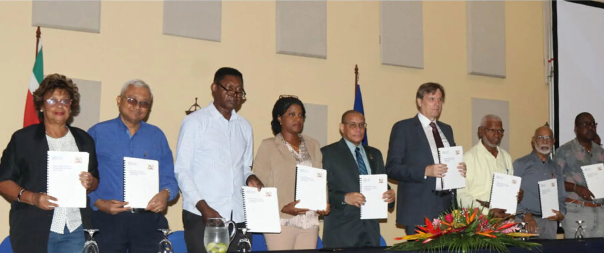 Group photo of people standing holding a document
