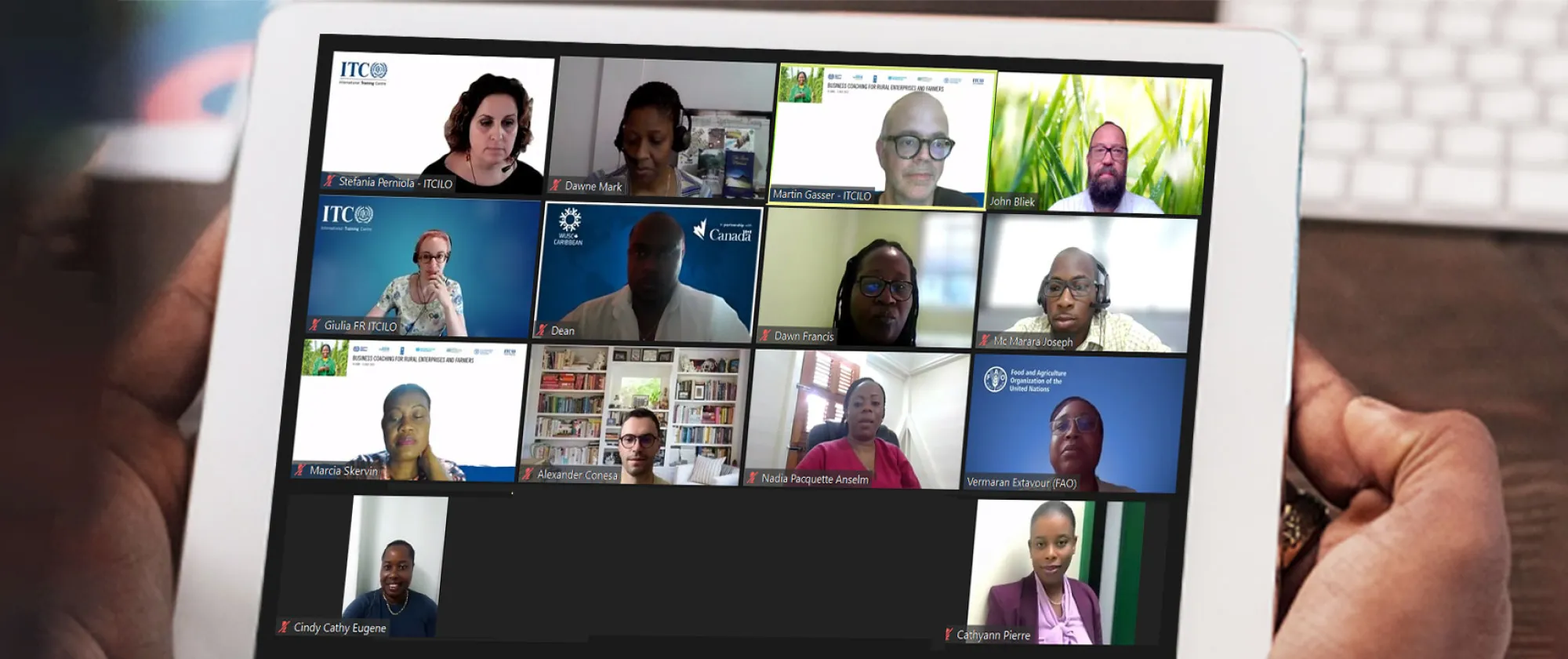Hands holding a tablet with the screen in a virtual meeting with participants