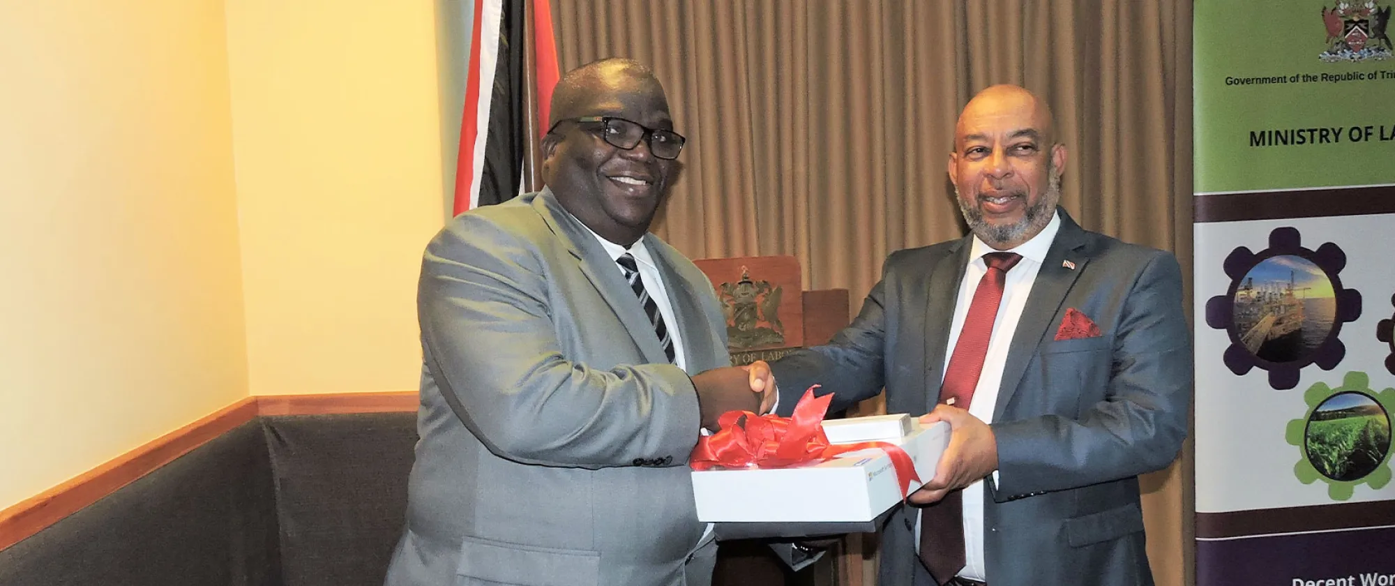 Photo of two men shaking hands while holding a package