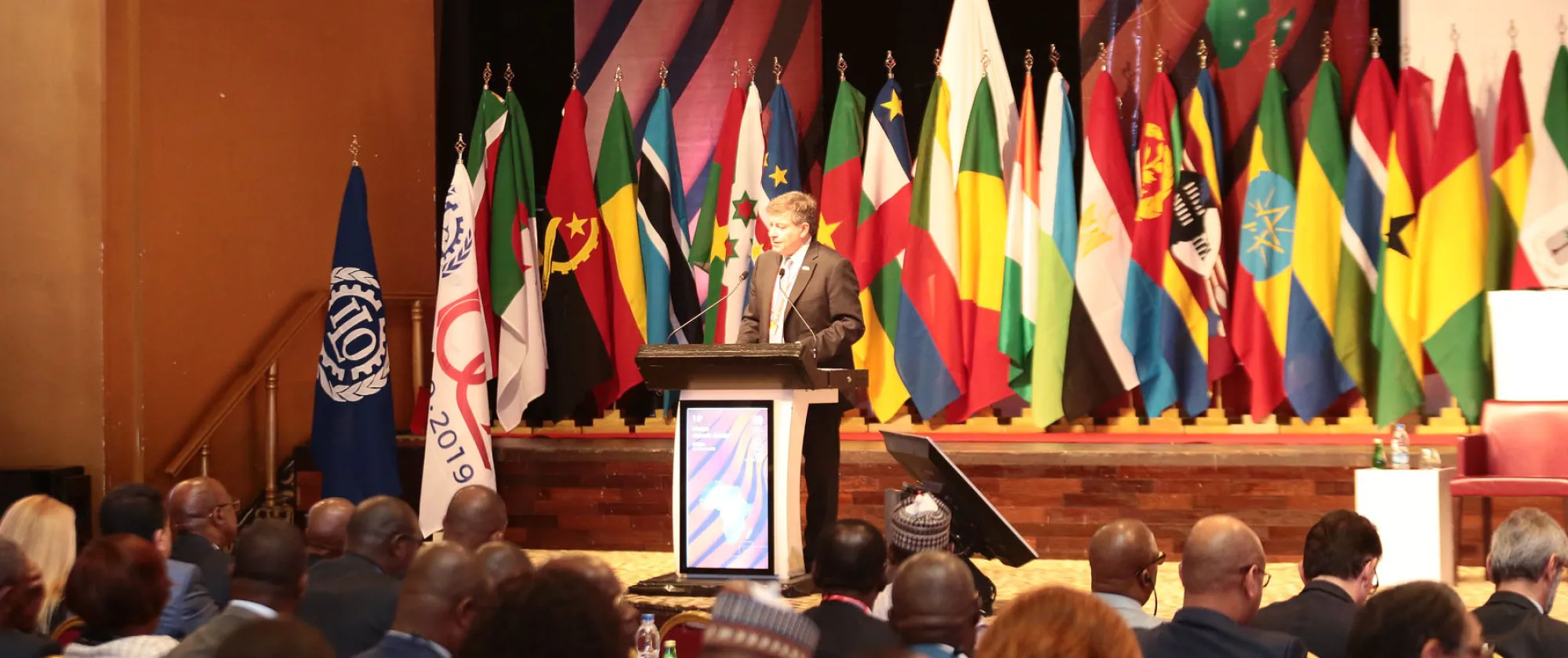 ILO Director-General Guy Ryder stands in front of a podium while speaking at the opening of the 14th ILO African Regional Meeting in Abidjan, Ivory Coast.