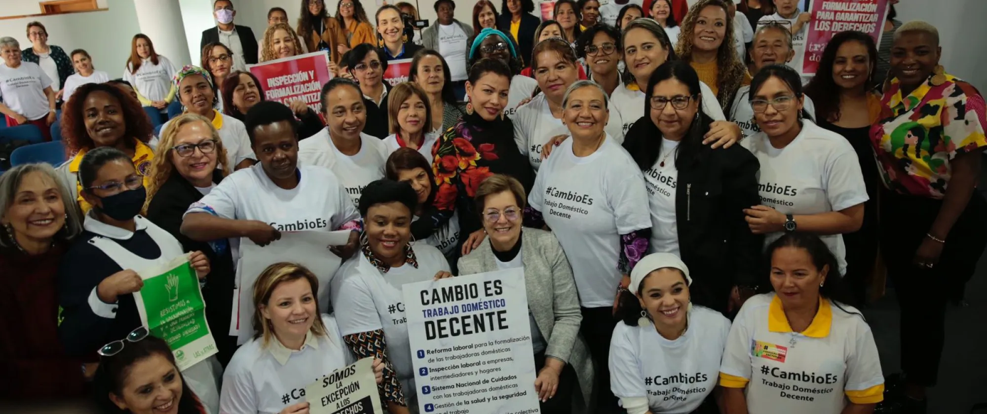 Foto grupal de trabajadoras domésticas remuneradas en Colombia sosteniendo carteles con el llamado Cambio es Trabajo Doméstico Decente junto con la ministra del Trabajo Gloria Inés Ramírez