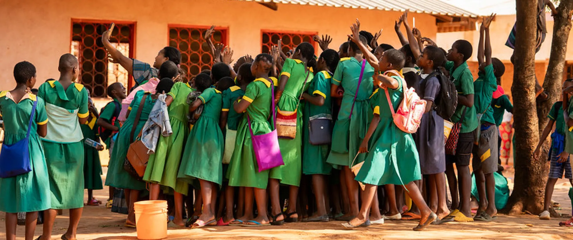 A lot of children in green uniform pose for a selfie in their schools