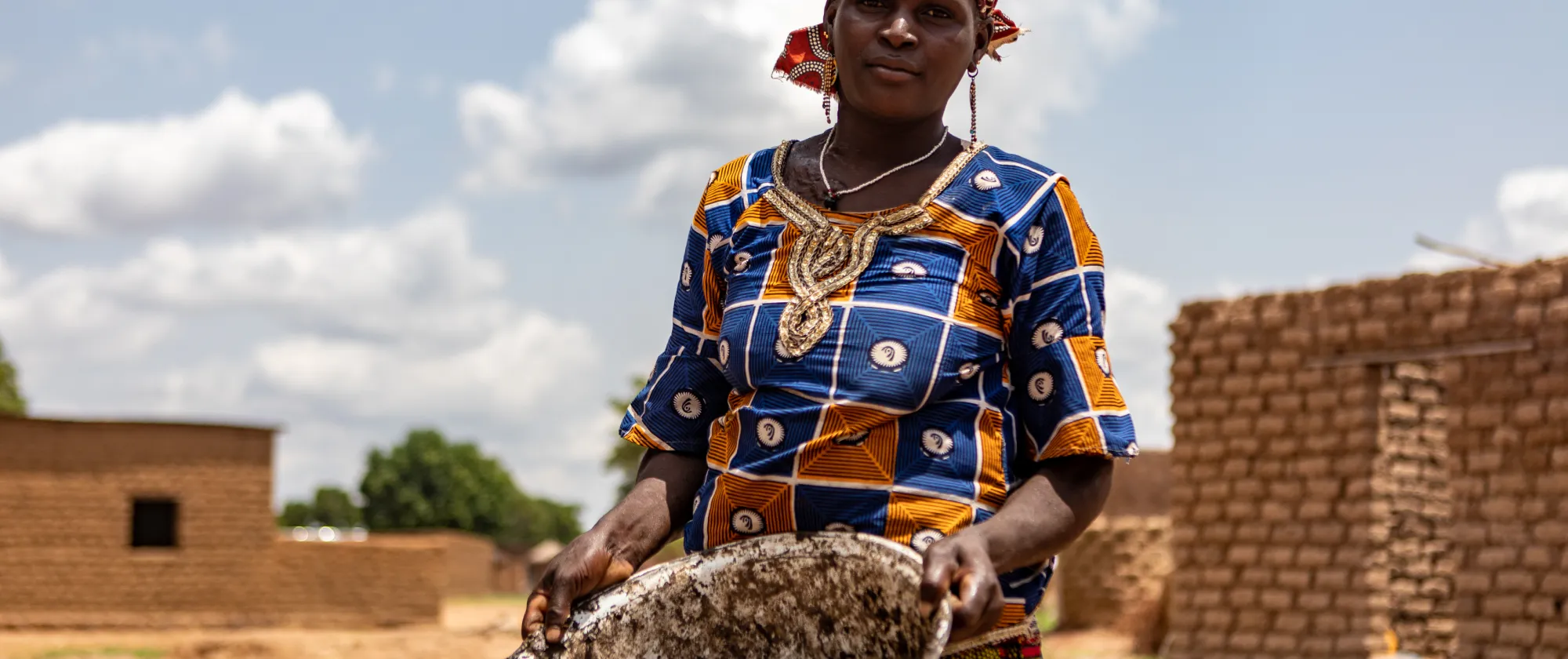 A woman holding a cup containing shea nuts in her village, Mali