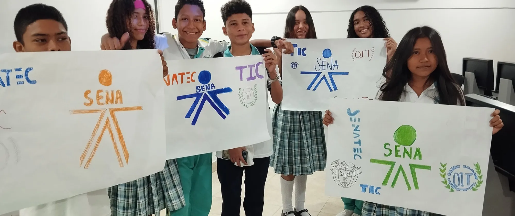 Foto grupas de jóvenes estudiantes de un colegio sosteniendo pancartas con los logos dibujados del SENA y OIT
