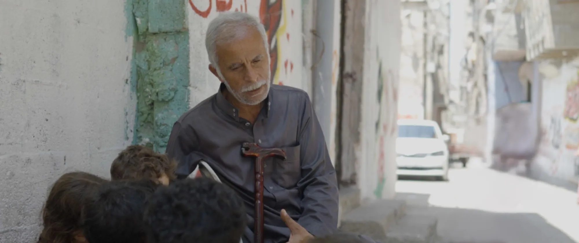 Older man speaking to children in the street 