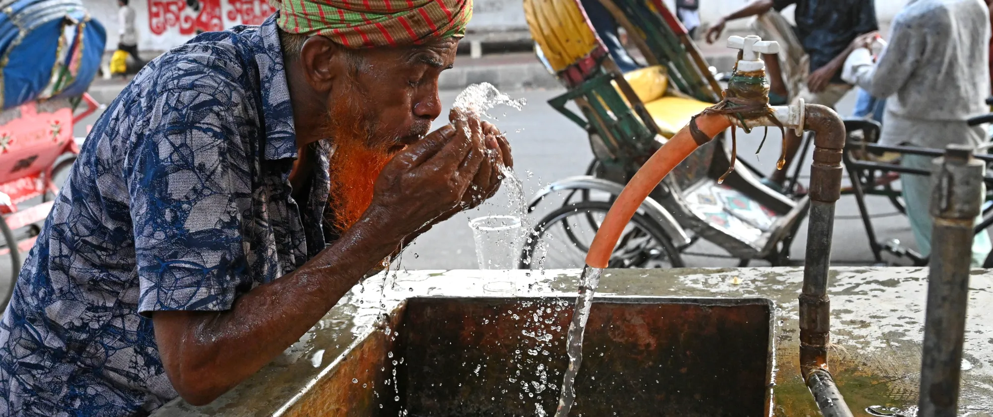 A rickshaw driver washing his face with water at a roadside water pipeline during heatwave weather in Dhaka, Bangladesh, on April 27, 2024