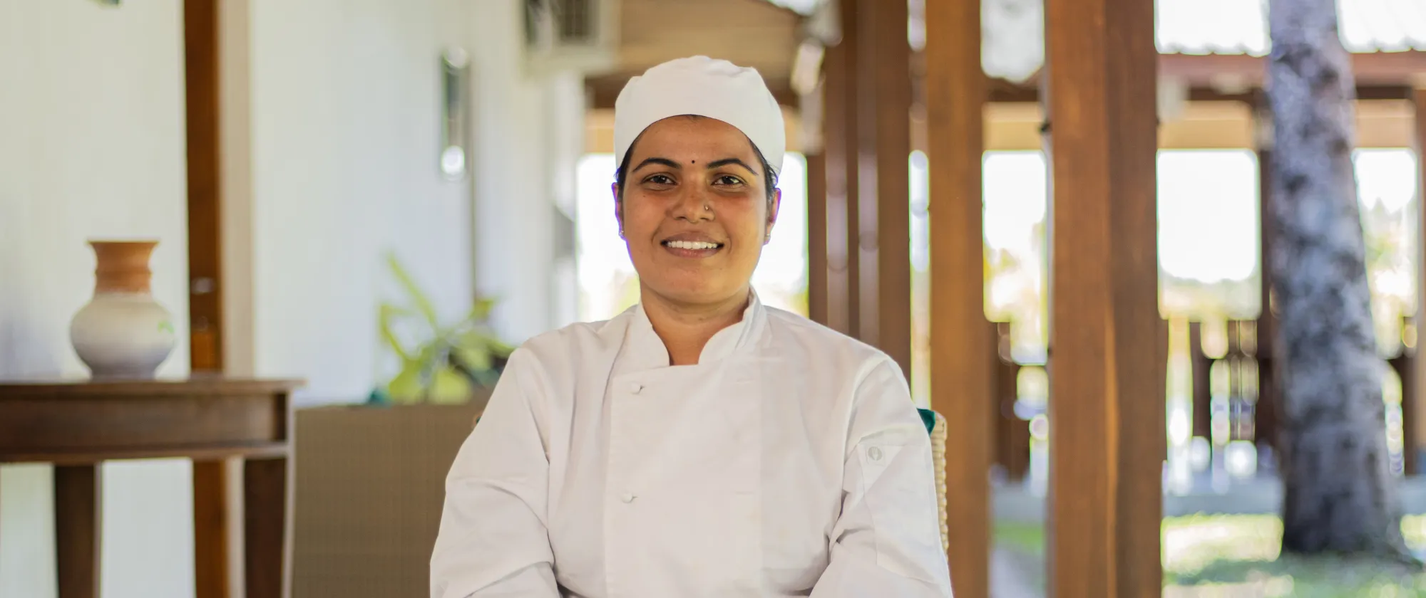 Young woman in chef attire smiles at camera
