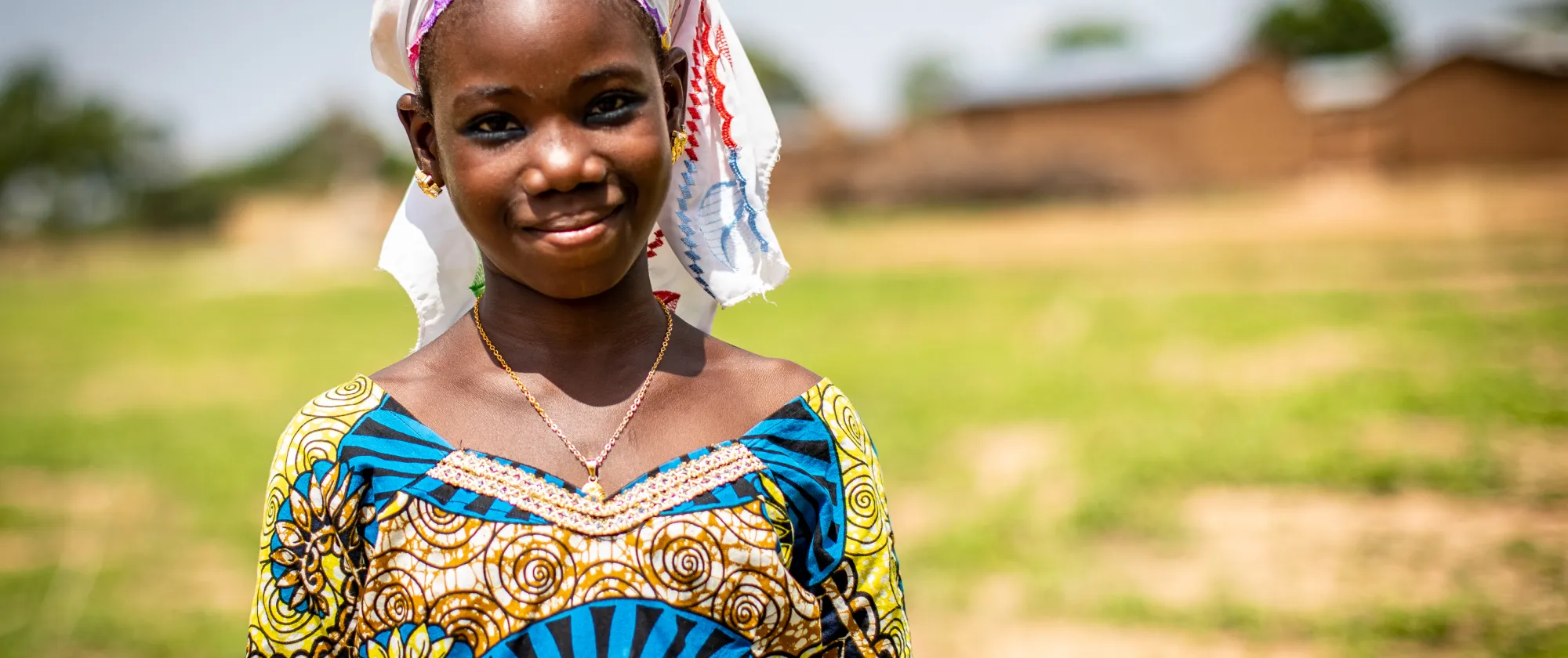 Young girl smiling, outside her village in Mali
